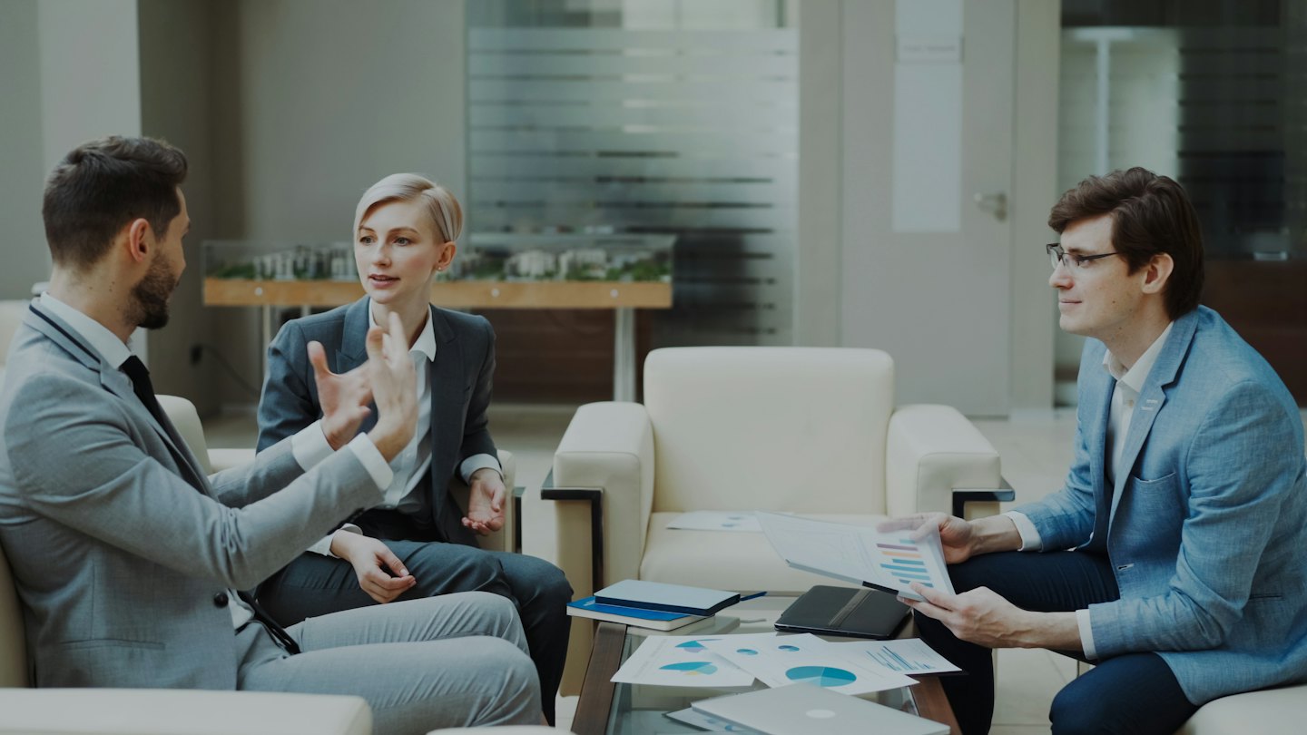 Profesionales de negocios discutiendo estrategia en una sala de estar moderna de oficina.